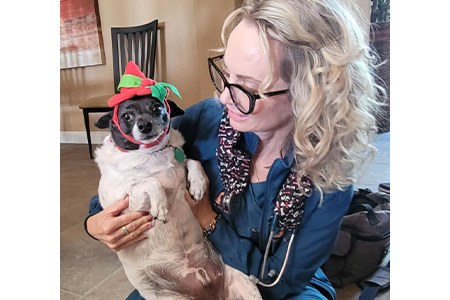 Dr. Bradshaw holding a small dog wearing a festive hat